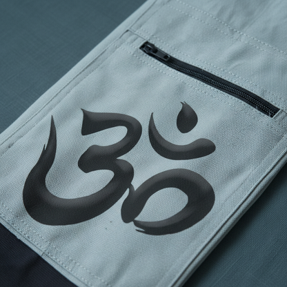 Close-up of white cotton Om yoga mat bag showing zipper pocket, stitching details, and sacred Om artwork on deep teal textured background. — for Carpe Diem Dream