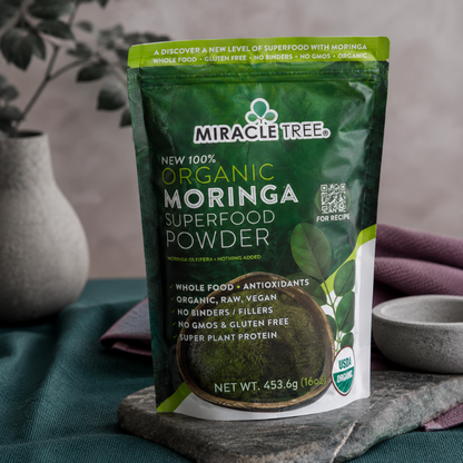 Organic Moringa Superfood Powder 16oz pouch shown close-up with textured packaging, front label detail, dark teal linen, mauve textile, and stone styling. — for Carpe Diem Dream