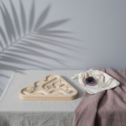 Wooden Ouroboros sensory meditation maze displayed with amethyst, clear quartz, and mauve linen in a botanical-inspired setting. — for Carpe Diem Dream