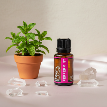Amber glass bottle of Peppermint Essential Oil styled beside small potted peppermint plant and clear crystal stones on soft neutral surface in natural light. — for Carpe Diem Dream