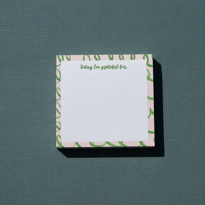 Square pink and green gratitude sticky note pad with “Today I’m grateful for” text displayed on a textured muted teal surface. — for Carpe Diem Dream