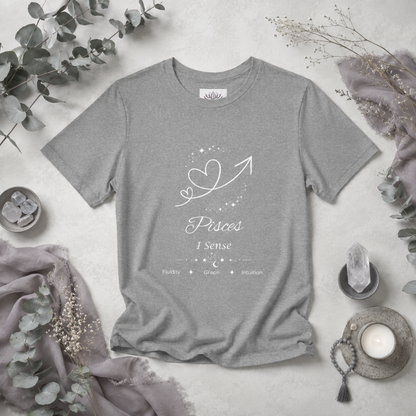 Pisces Rising I Sense zodiac T-shirt in Athletic Heather with white celestial heart and arrow artwork and Fluidity, Grace, Intuition text, styled in a cool-toned studio botanical flat lay. — for Carpe Diem Dream