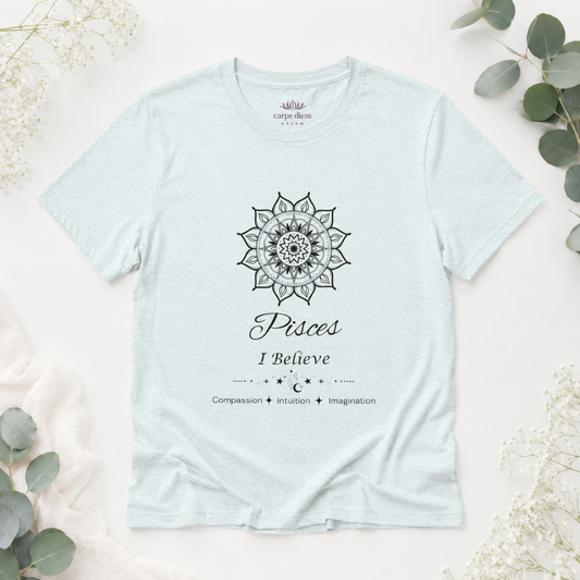 Pisces Sun I Believe zodiac T-shirt in heather ice blue with black sun-inspired mandala artwork and Compassion, Intuition, Imagination text, styled in a cool-toned studio botanical flat lay. — for Carpe Diem Dream