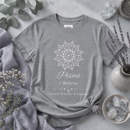 Pisces Sun I Believe zodiac T-shirt in athletic heather with white sun-inspired mandala artwork and Compassion, Intuition, Imagination text, styled in a cool-toned studio botanical flat lay. — for Carpe Diem Dream