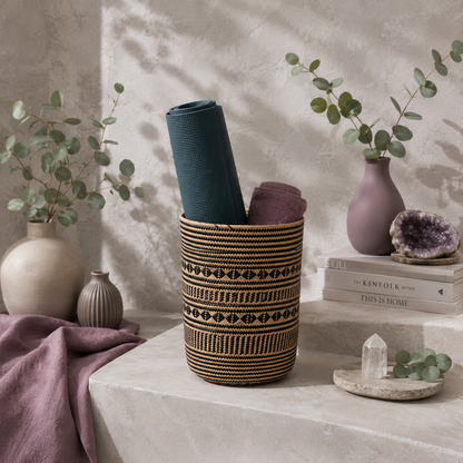 Praya handwoven rattan basket displayed in the CDD botanical studio with a rolled dark teal yoga mat, mauve towel, eucalyptus, matte ceramics, and natural stone styling. — for Carpe Diem Dream