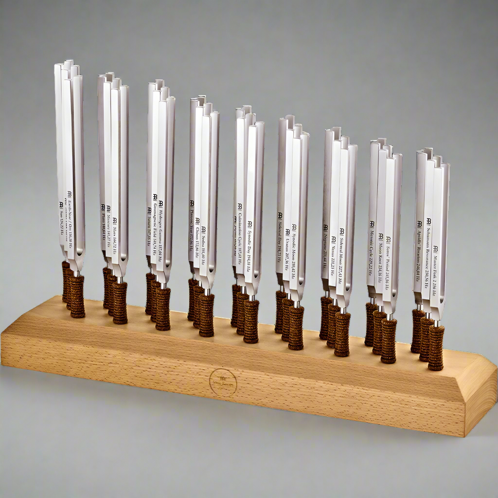 Twenty-seven weighted planetary therapy tuning forks standing upright in a wooden holder against a light neutral background. — for Carpe Diem Dream