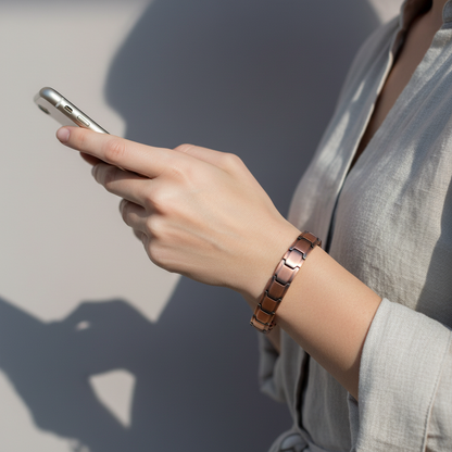 A person wearing a pure copper magnetic bracelet while holding a smartphone, showing everyday use in natural light. — for Carpe Diem Dream