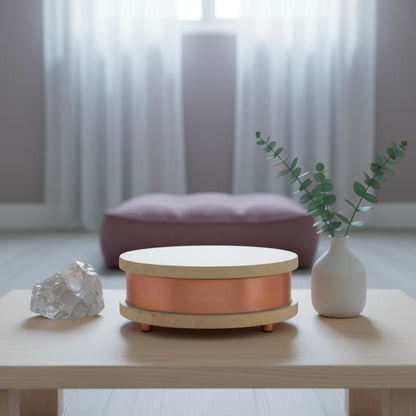 A Qi-Home Cell EMF protection device with copper body and light wood top and base displayed on a table with a crystal and vase in a soft, serene meditation-inspired living space with diffused natural light. — for Carpe Diem Dream