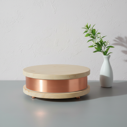 A Qi-Home Cell EMF protection device with copper body and light wood top and base displayed on a clean neutral surface with a small vase and soft natural lighting. — for Carpe Diem Dream