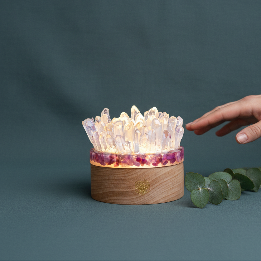 A glowing quartz and pink tourmaline lamp on a muted teal surface with a hand reaching toward the crystals, offering both scale and symbolism. — for Carpe Diem Dream