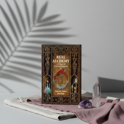 The paperback book Real Alchemy displayed beside clear quartz and amethyst crystals on layered mauve and linen fabric with botanical shadows and soft editorial lighting. — for Carpe Diem Dream