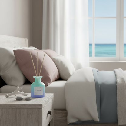 A frosted glass reed diffuser in a soft blue gradient bottle placed on a bedside table next to a bed with ocean view through a window and soft natural light. — for Carpe Diem Dream