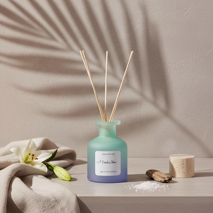 A frosted glass reed diffuser in a soft blue gradient bottle with natural reed sticks styled with a lily, folded fabric, and sea salt on a neutral textured surface with botanical shadows. — for Carpe Diem Dream
