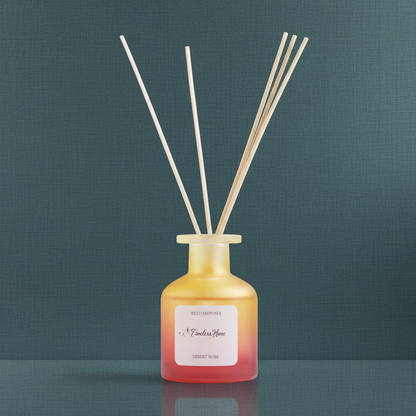 A frosted glass reed diffuser in a warm yellow to coral gradient bottle with natural reed sticks displayed on a muted teal textured background in soft natural light. — for Carpe Diem Dream