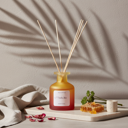 A frosted glass reed diffuser in a warm yellow to coral gradient bottle with natural reed sticks styled with rose petals, honeycomb, and soft fabric under botanical shadows on a textured neutral surface. — for Carpe Diem Dream