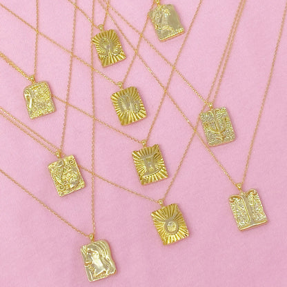 Reversible gold zodiac necklaces with constellation pendant, showing both polished and engraved sides on pink background for Carpe Diem Dream
