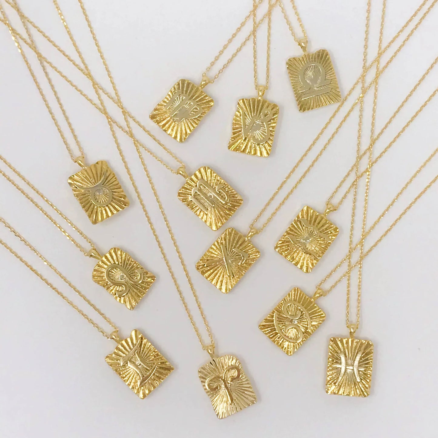 Reversible gold zodiac necklaces with constellation pendant, showing both polished and engraved sides on white background for Carpe Diem Dream