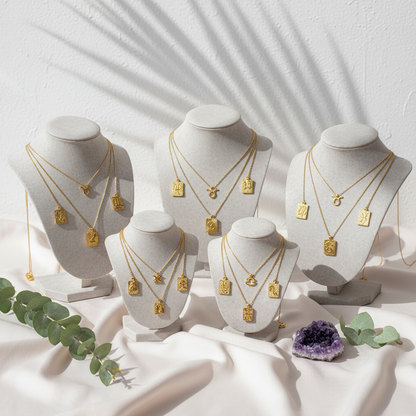 Reversible gold zodiac necklaces with constellation pendant, showing both polished and engraved sides on botanical pink silk with amethyst background.