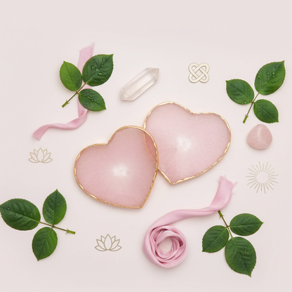 Two heart-shaped rose quartz coasters with gold edging arranged flatlay style with leaves, ribbon, and crystals on soft pink backdrop. — for Carpe Diem Dream