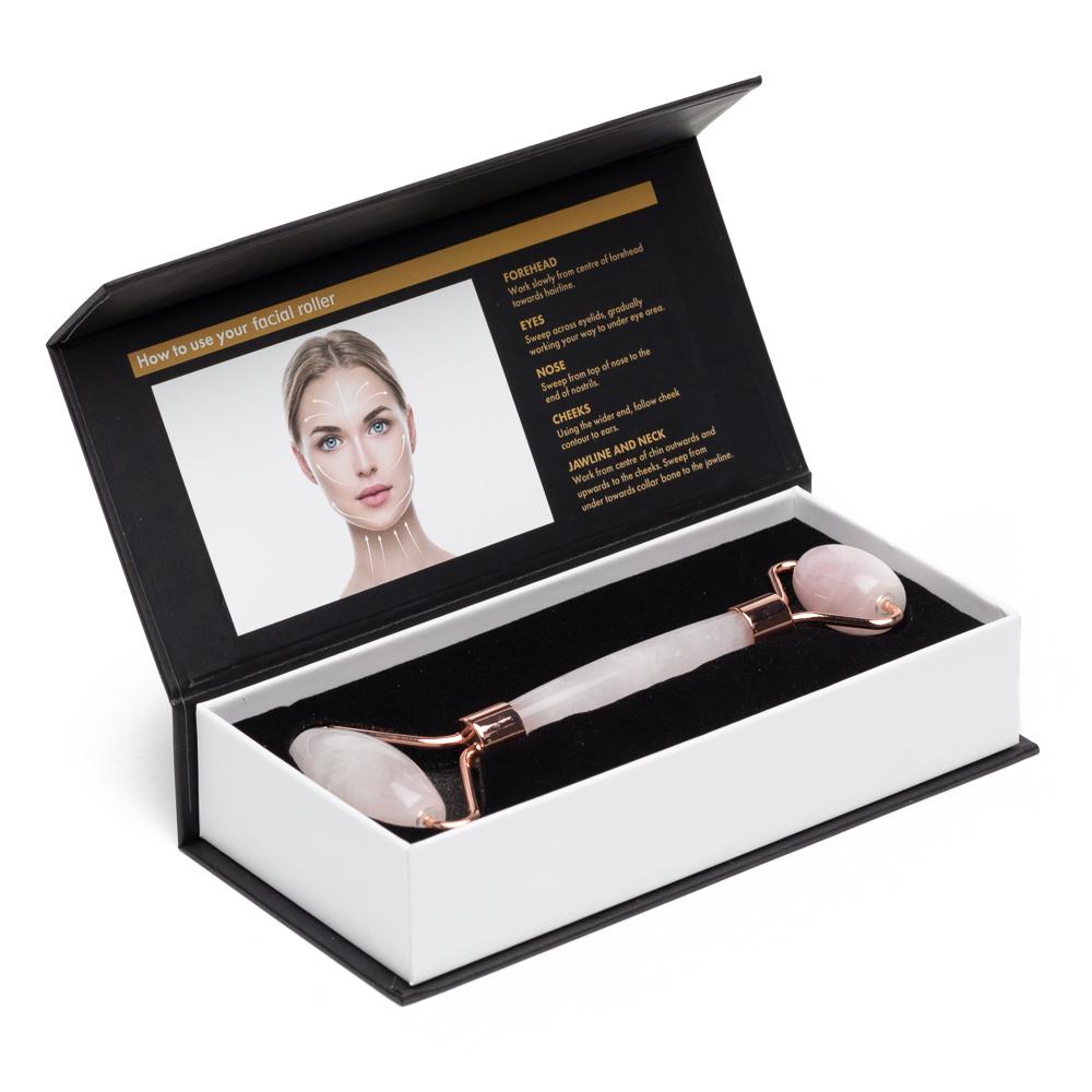 A rose quartz dual-ended facial roller displayed inside a black and white presentation gift box with foam insert. — for Carpe Diem Dream
