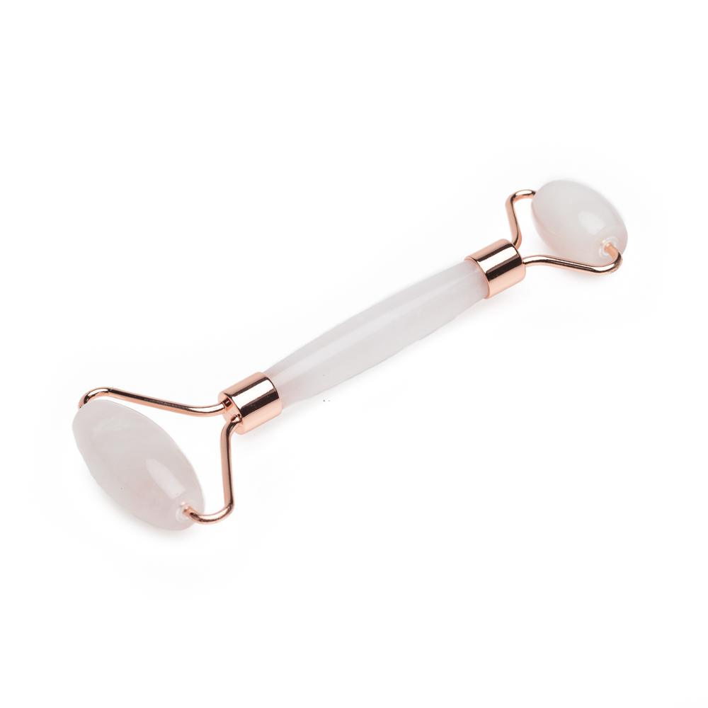 A dual-ended rose quartz facial roller with polished crystal rollers and rose gold frame displayed on a clean white background. — for Carpe Diem Dream