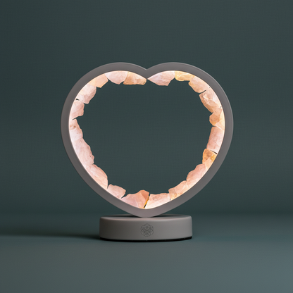 A heart-shaped rose quartz lamp glowing softly on a muted teal surface in diffused natural light. — for Carpe Diem Dream