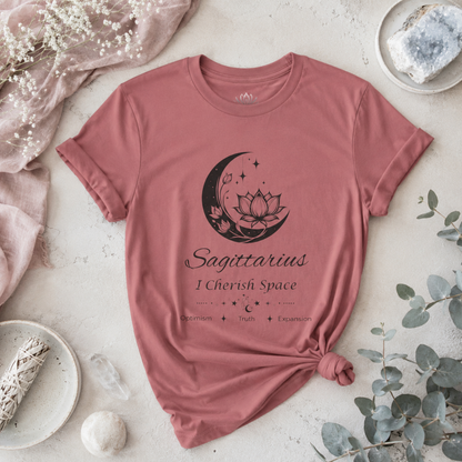 Sagittarius Moon I Cherish Space zodiac T-shirt in mauve with black moon-inspired lotus, floral, and celestial artwork and Optimism, Truth, Expansion text, styled in a cool-toned studio botanical flat lay. — for Carpe Diem Dream