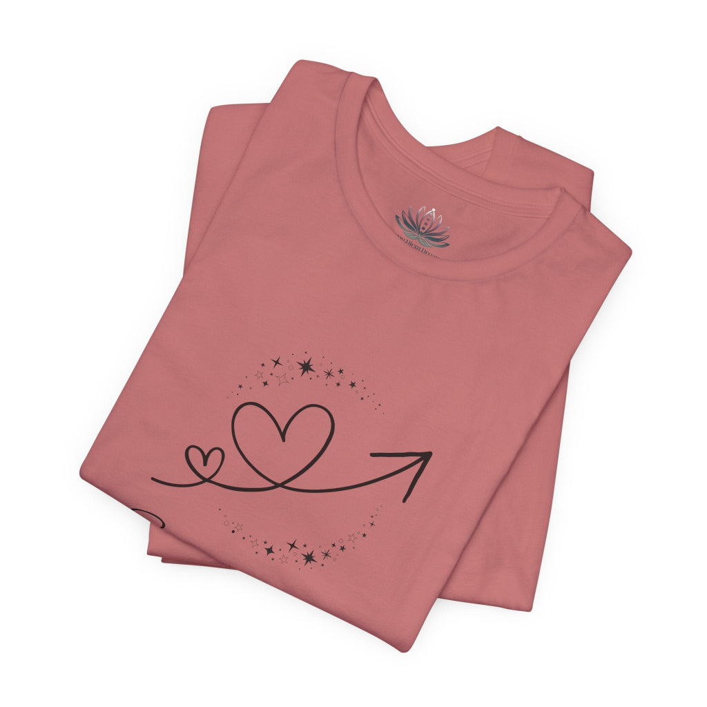 Sagittarius Rising I Explore zodiac T-shirt in mauve with black celestial heart and arrow artwork, shown folded in a supplier mockup. — for Carpe Diem Dream