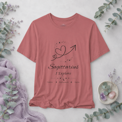 Sagittarius Rising I Explore zodiac T-shirt in mauve with black celestial heart and arrow artwork and Candor, Enthusiasm, Vision text, styled in a cool-toned studio botanical flat lay. — for Carpe Diem Dream