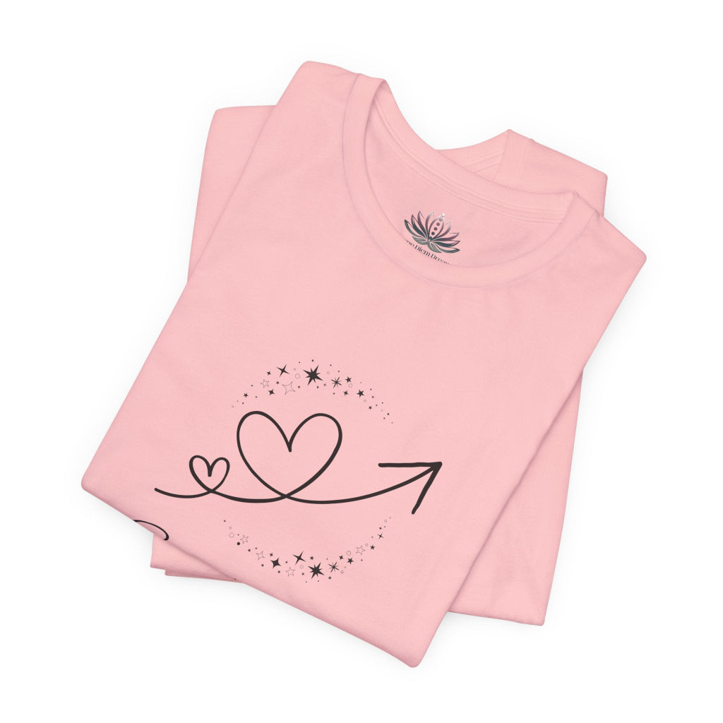 Sagittarius Rising I Explore zodiac T-shirt in pink with black celestial heart and arrow artwork, shown folded in a supplier mockup. — for Carpe Diem Dream