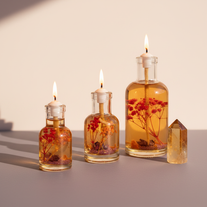 Three Sagittarius zodiac oil candles in different sizes with warm orange botanicals in clear glass vessels are displayed together on a neutral surface with a golden crystal accent. — for Carpe Diem Dream