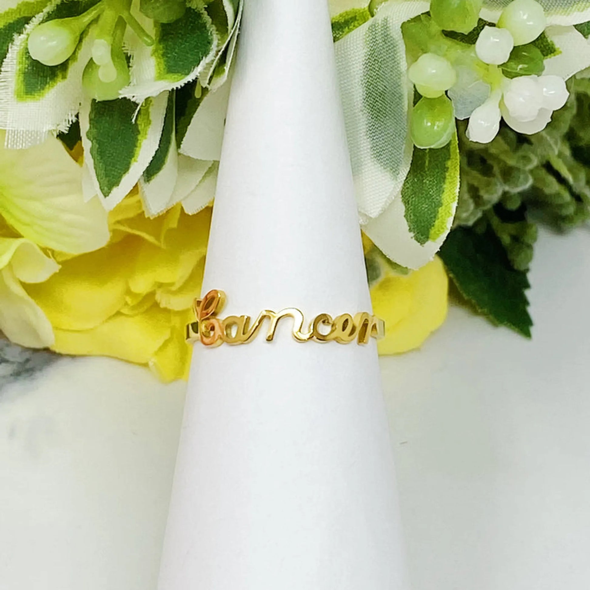 18K gold Scripted Zodiac Ring featuring delicate cursive lettering of zodiac Cancer, displayed on white botanical background for Carpe Diem Dream