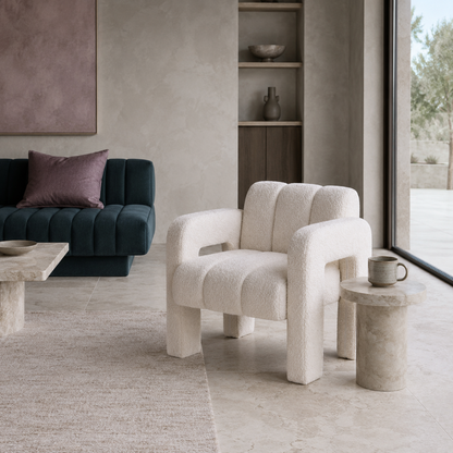 Beige sculpted bouclé upholstered accent chair styled in a cool-toned living room with dark teal seating, mauve accents, stone surfaces, and soft natural light. — for Carpe Diem Dream
