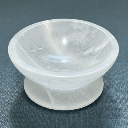 A close-up view of a translucent white selenite crystal bowl with pedestal showing its smooth polished interior. — for Carpe Diem Dream