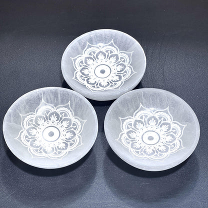 Three translucent white selenite mandala lotus bowls arranged together on a dark textured surface. — for Carpe Diem Dream