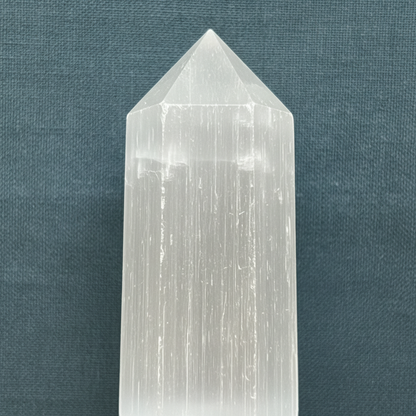 A close-up view of the pointed top and natural striated texture of a Moroccan selenite obelisk crystal. — for Carpe Diem Dream