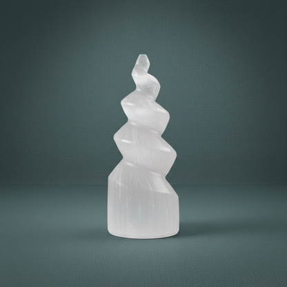 A carved selenite spiral tower standing upright against a muted teal background. — for Carpe Diem Dream