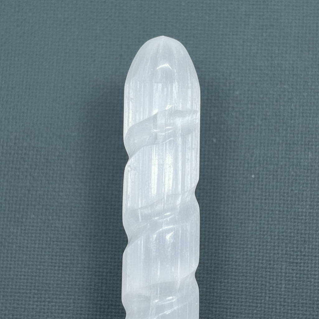 A close-up view of a translucent white selenite spiral wand showcasing its carved tip and natural striations. — for Carpe Diem Dream