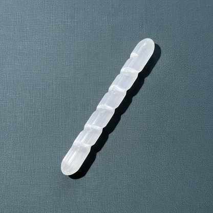 A translucent white selenite spiral wand displayed diagonally on a muted sage background. — for Carpe Diem Dream