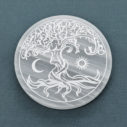 A close-up view of a translucent white selenite Tree of Life round charging plate showing its engraved design and smooth polished surface. — for Carpe Diem Dream