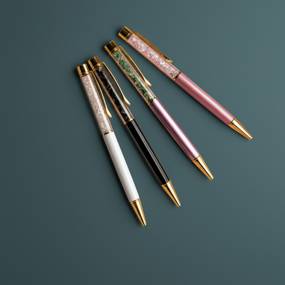 A set of self-cleansing crystal ballpoint pens with gold accents displayed on a deep teal background. — for Carpe Diem Dream