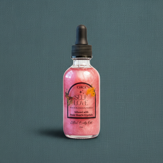 Pink Self Love Ritual Body Oil bottle with rose quartz crystals and black dropper displayed upright on a muted teal linen background. — for Carpe Diem Dream