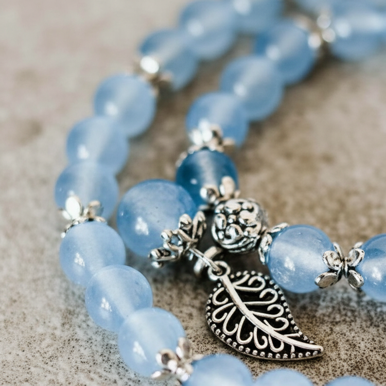 Close-up of Serenity Leaf Chalcedony gemstone bracelet showing silver leaf charm on textured stone surface with soft shadow. — for Carpe Diem Dream