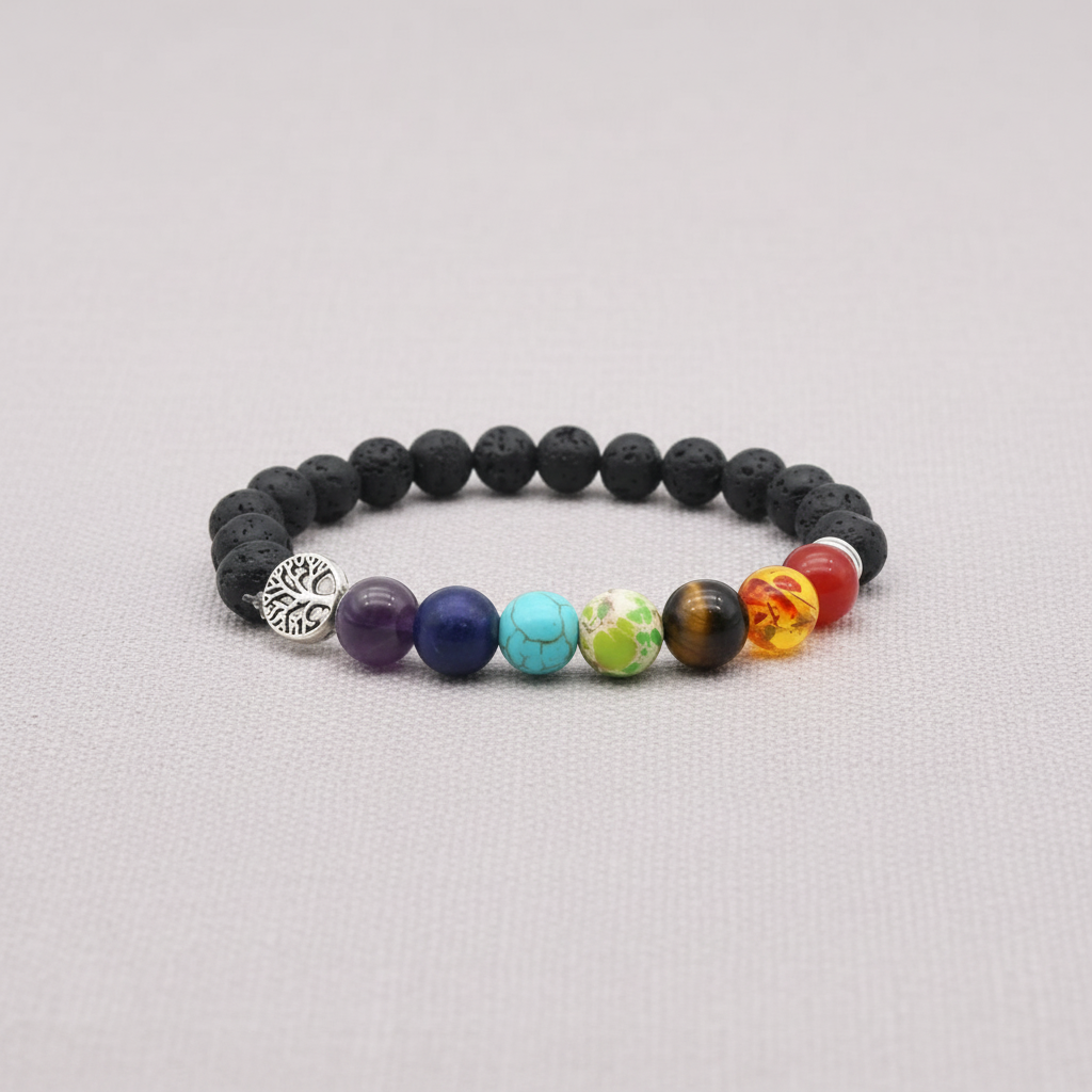 A black lava stone stretch bracelet with multicolored chakra beads and a silver Tree of Life charm displayed on a light fabric background. — for Carpe Diem Dream