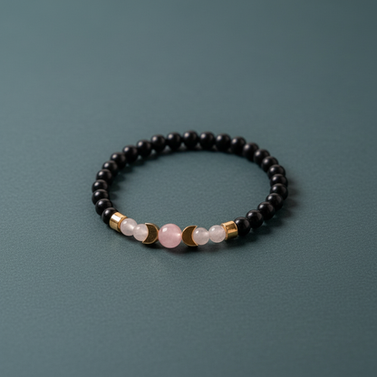 A shungite beaded bracelet accented with rose quartz and moonstone beads arranged on a muted teal background.— for Carpe Diem Dream