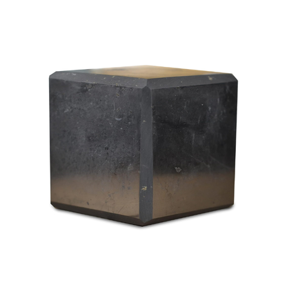 Black shungite cube displayed on a clean white background with subtle reflection, showing natural stone texture and geometric form. — for Carpe Diem Dream