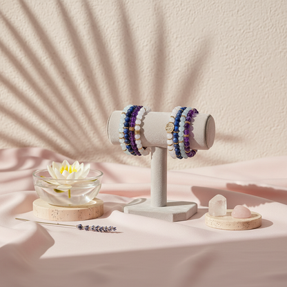 A four-bracelet gemstone stack displayed on a soft beige stand with white, amethyst, icy blue, and deep blue beads, set in a botanical studio scene with soft shadows and natural accents. — for Carpe Diem Dream
