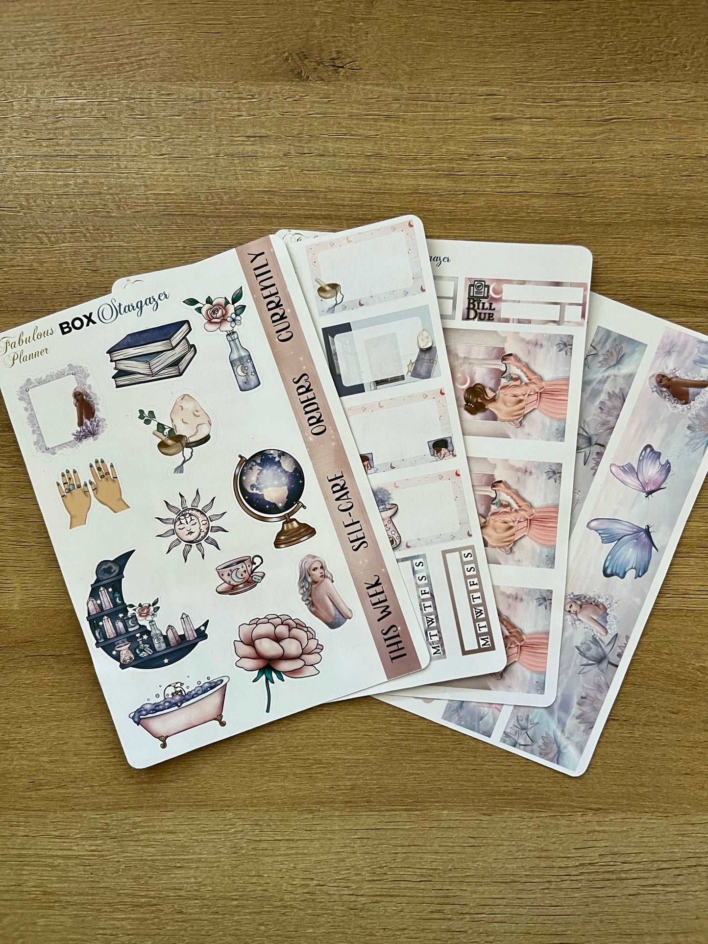 our 4x6 stargazer planner sticker sheets featuring mystical illustrations, moon phases, crystals, and celestial motifs arranged on a wooden background. — for Carpe Diem Dream