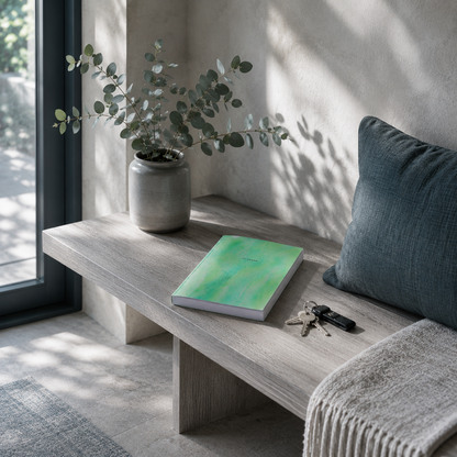 Start Anytime Undated 52-Week Planner by Big Fish Planners resting closed on a cool ash wood entryway bench in a calm, intentionally organized home, styled with a muted teal cushion, ceramic vase with eucalyptus stems, and a set of keys under soft diffused daylight, conveying a sense of clarity, forward momentum, and peaceful accomplishment while preserving the planner's original cover artwork and realistic paperback proportions — for Carpe Diem Dream