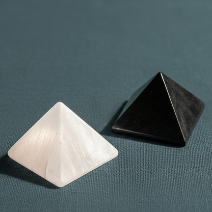 A close-up of white and black crystal pyramids resting on a muted teal textured surface under soft natural light. — for Carpe Diem Dream
